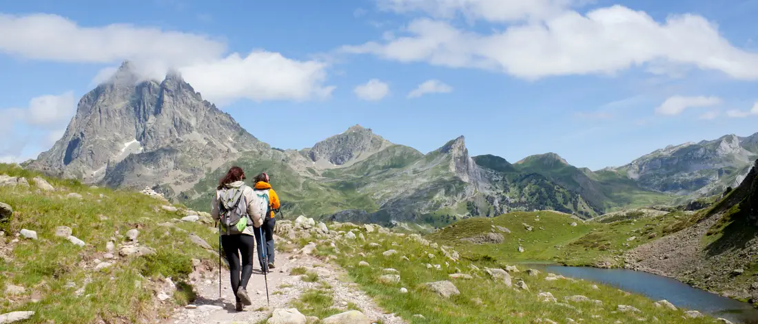 Two hikers with trekking poles on a mountain path