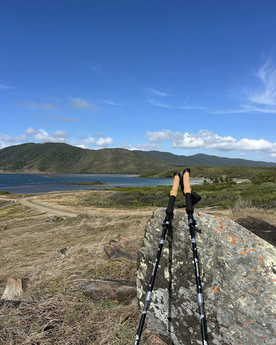 BERGBOUND Wanderstöcke an einem Felsen mit Blick über die Bucht