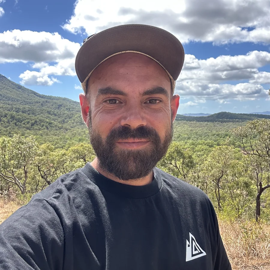 Kai Freund, founder of BERGBOUND, wearing a BERGBOUND shirt in front of bushland in Australia
