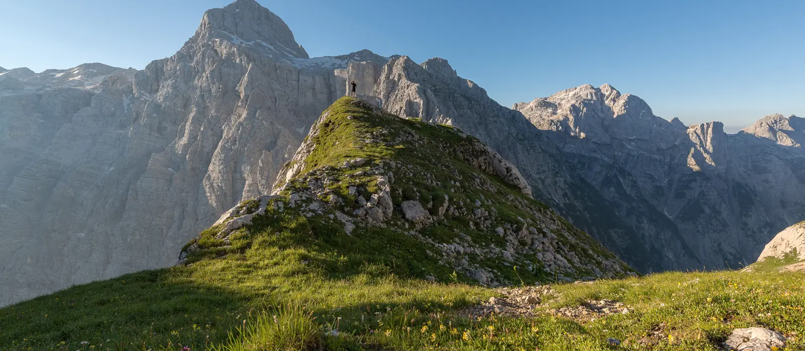 Wanderer auf einem Grat vor alpinem Bergpanorama